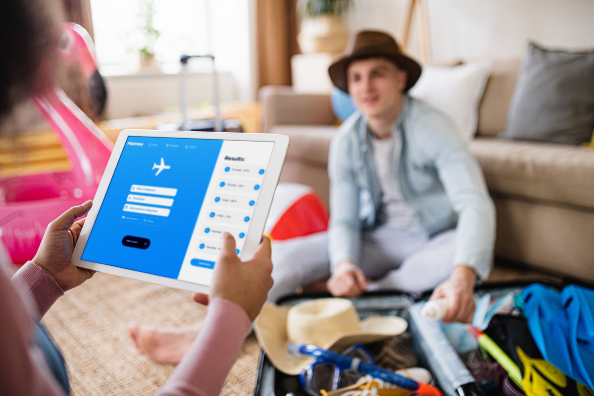 packing for a trip while also looking up flights on a tablet