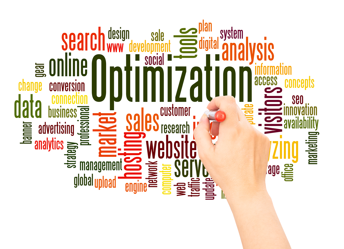 This image shows a hand holding a marker near a word cloud with the word "Optimization" highlighted in dark green, creating a clean and conceptual image. The hand is the only human element, its precise action emphasizing the theme. Various business and marketing-related terms surround the main focus. 