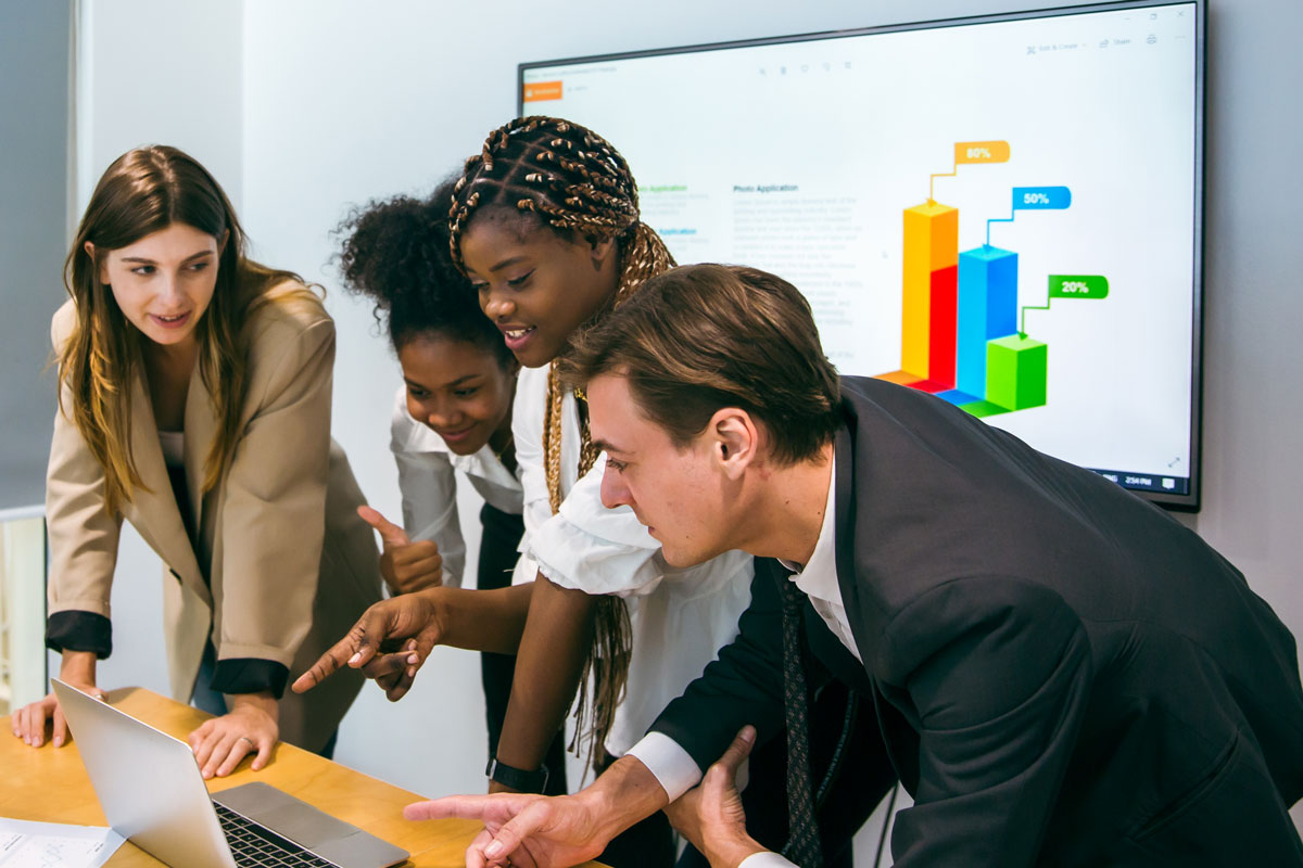 A small DMO or tourism marketing team gathered around a screen, reviewing a content strategy or analytics dashboard. Modern office, collaborative setting.