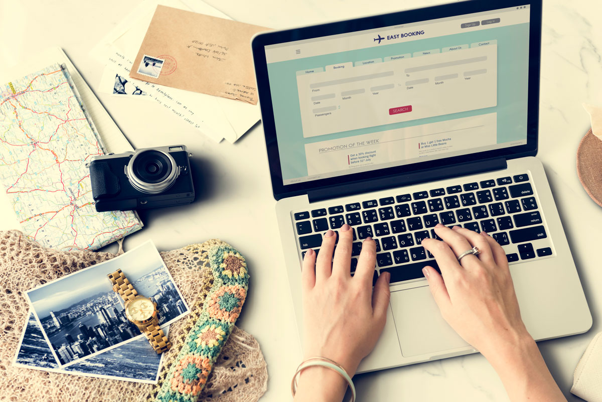 travel booking on laptop with camera and maps